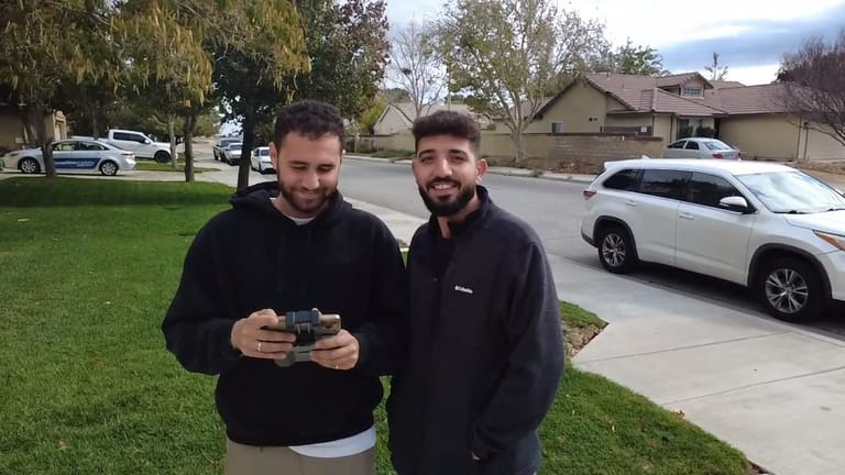 Two CaliPeak Roofing team members reviewing drone roof footage outside a client home
